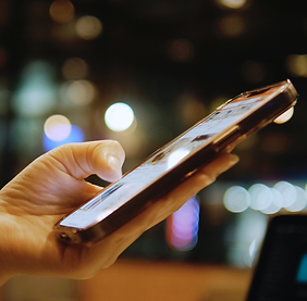 Hand holding a smartphone with blurred city lights in the background