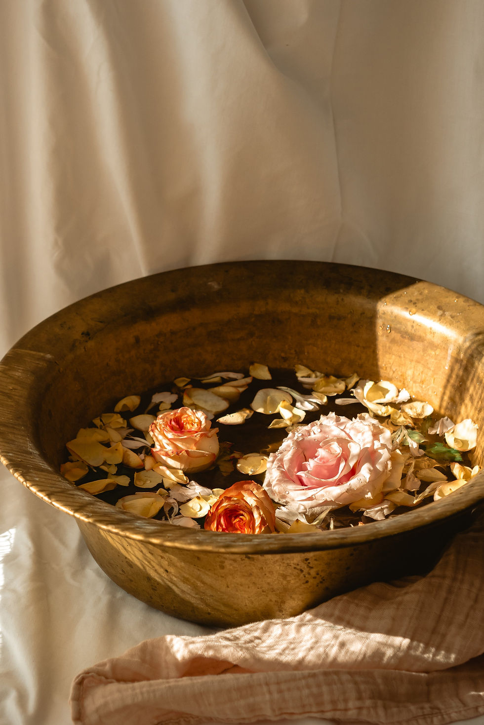 A brass bowl with water and roses floating in it