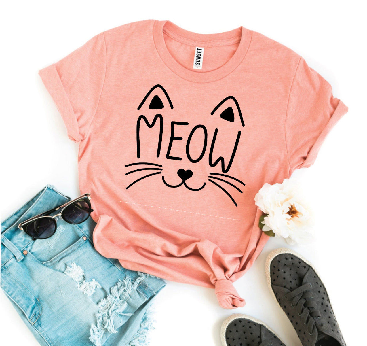 Pink t-shirt with a cat face and "MEOW" text, paired with jeans and shoes.