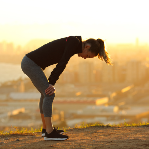 A woman is bent forward in silhouette exhausted from finishing a marathon in Ottawa.