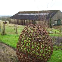 Large handcrafted garden sculpture shaped like an open lattice egg, made from interlinked circular metal pieces by The Welding Carpenter in Kent