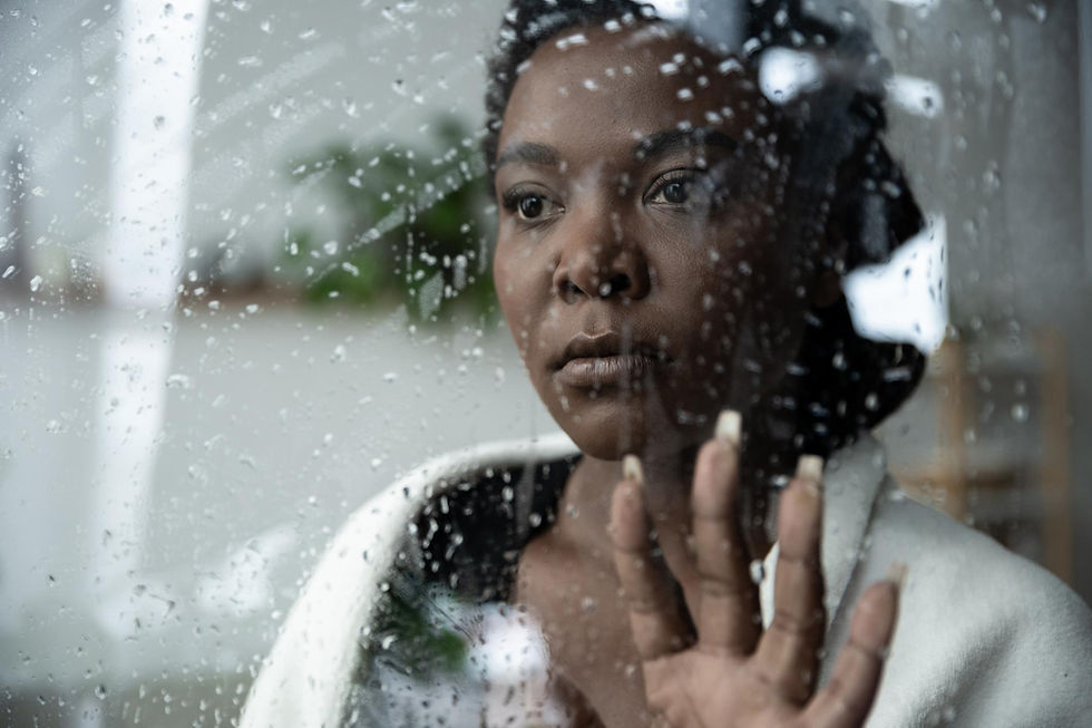Una mujer pensativa mira a través de una ventana cubierta de gotas de lluvia mientras apoya la mano sobre el vidrio. Su expresión transmite introspección emocional, contemplación y una sensación silenciosa de búsqueda interior.