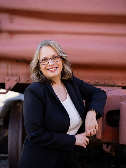 Teri Nelson Coach, sitting down, wearing a dark suit with white top