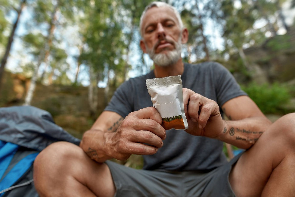 man eating a energy bar while sitting in the mountains