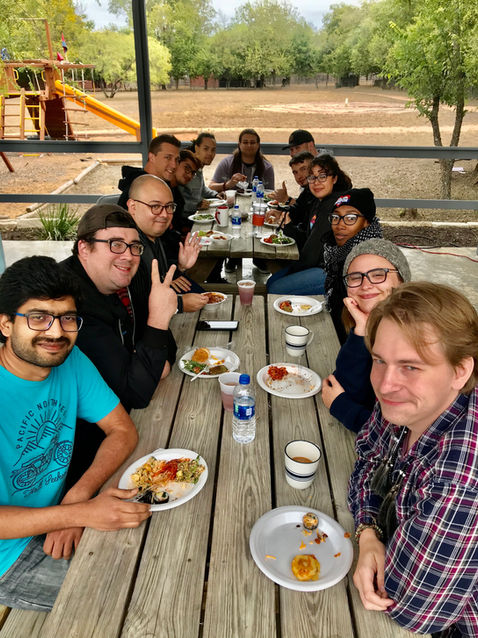 Young people eating lunch at outdoor table.