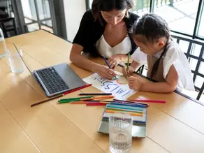 Mother helping daughter with a “miss you” drawing at home—symbolizing parent involvement in early learning and benefits of Florida Pre-K programs
