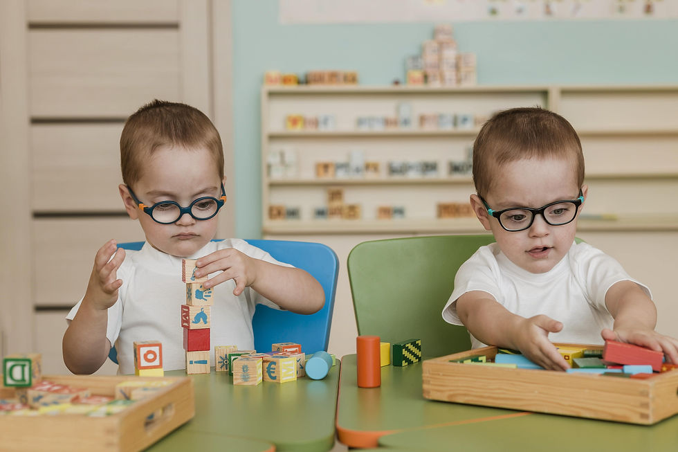 Two toddlers wearing glasses playing with educational blocks — illustrating the differences in Toddler Daycare vs. Infant Daycare.