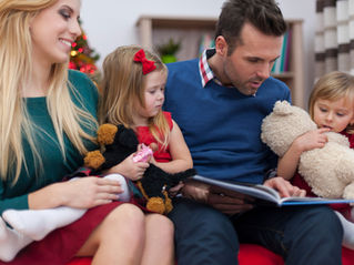 Parents reading a book with their children at home, representing a helpful Guide to Pre-K in Pembroke Pines and early childhood learning preparation.
