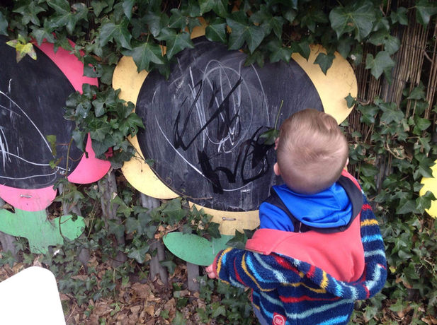 child drawing outside on a board