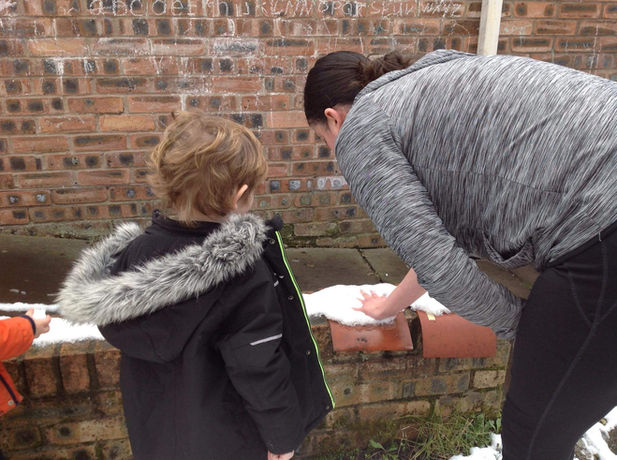 child and adult outside touching snow