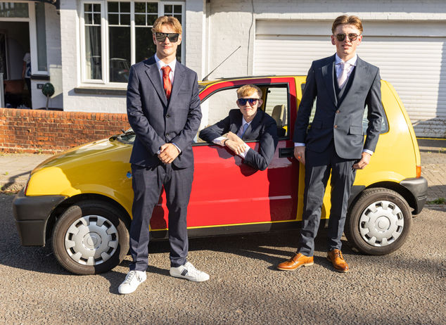 boys posing next to an old car 