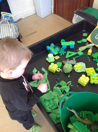 child playing with a selection of green items