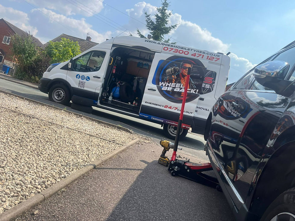 Car with a missing wheel being serviced next to a van, with tools and equipment laid out nearby.