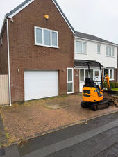 Mini excavator parked on a brick driveway during renovation