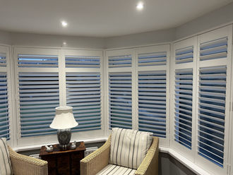 White bay window shutters in a cozy living room