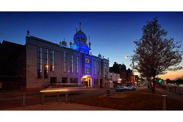 Grand classical building lit up at dusk with streetlights in the foreground