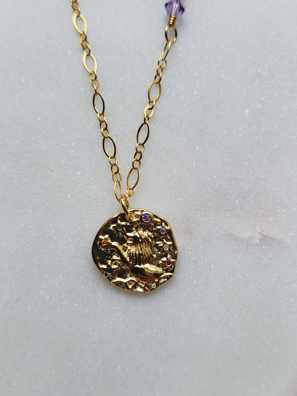 Thumbnail: Gold necklace with gold leo zodiac sign pendant with pink, blue, and purple wire wrapped crystals