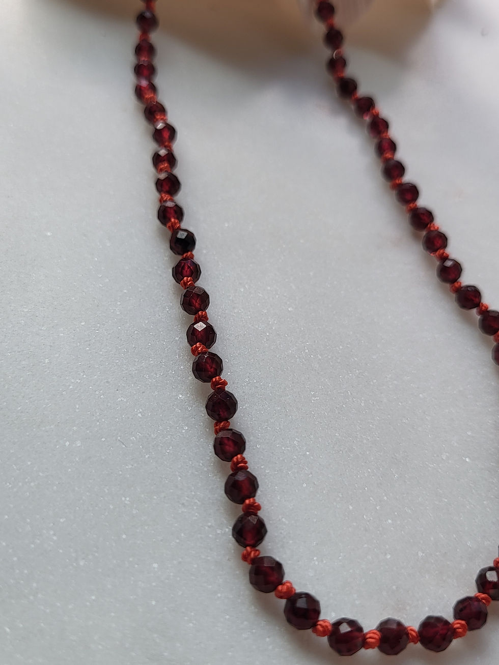 Thumbnail: Red garnet beaded necklace on red silk knotted cord