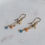Thumbnail: Gold chain dangle earrings with faceted aquamarine gemstones, pink freshwater pearls, and delicate gold starfish