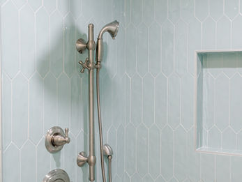 Custom coastal shower with aqua picket tile and upscale fixtures in coastal luxury retreat by waterfront builder, Coastline Signature Homes.