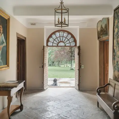 Architecte Versailles expert restauration châteaux demeures historiques : hall entrée château Biscay Pays Basque, meubles anciens conservés, tapisserie murale XVIIIe, sol pierre naturelle, chauffage sol invisible, porte bois sculptée quincaillerie origine, murs crème - Cabinet Antoine de Gironde architecte patrimoine Versailles secteur sauvegardé