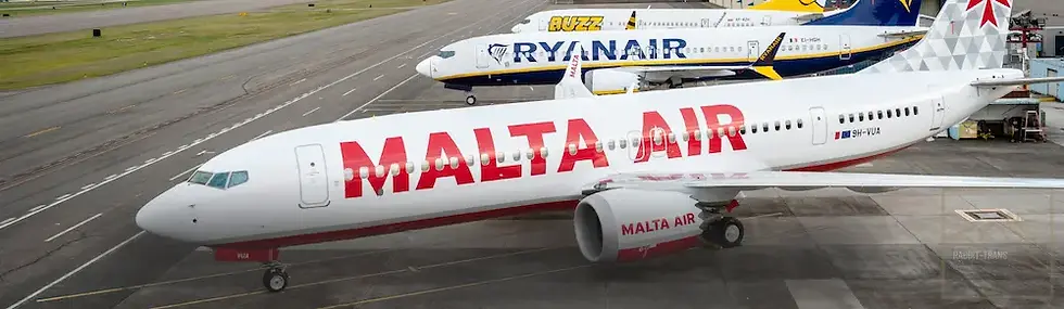 Samolot Malta Air na płycie lotniska, obok Ryanaira i Buzz. Białe kadłuby z jaskrawymi napisami. Dzień, tło lotniskowe.