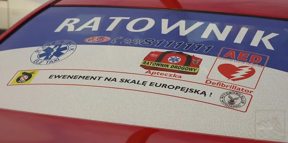 A sticker on the rear window of a car with the word "RESCUER," a phone number, and symbols for a first aid kit and an AED. The slogan: "A UNIQUE EXPERIENCE ON A EUROPEAN SCALE!"