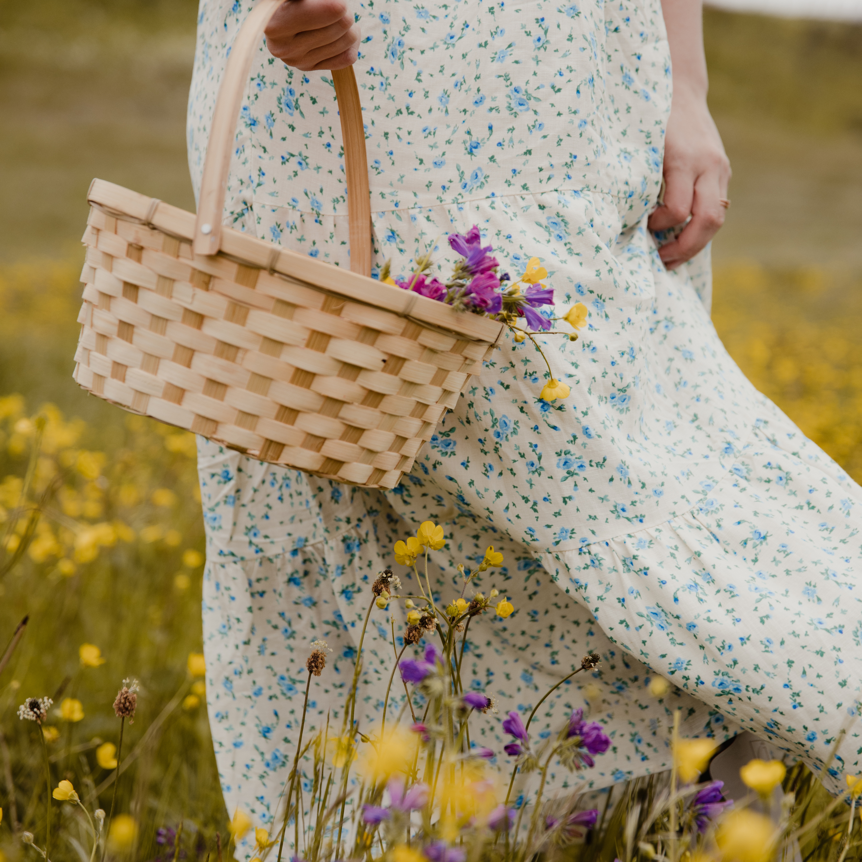 woman carrying flower basket through flower field