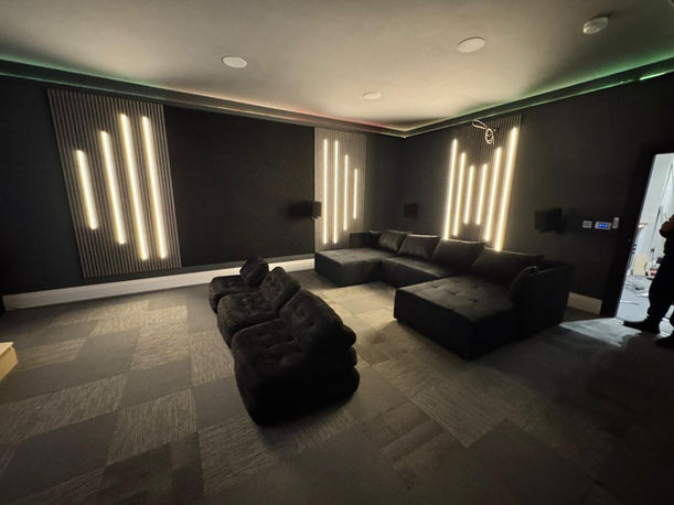 Sleek home theater room, large dark sectional sofa, vertical LED lights.