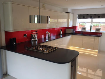 Clean, modern kitchen featuring white cabinets, black countertops, and red splashback.