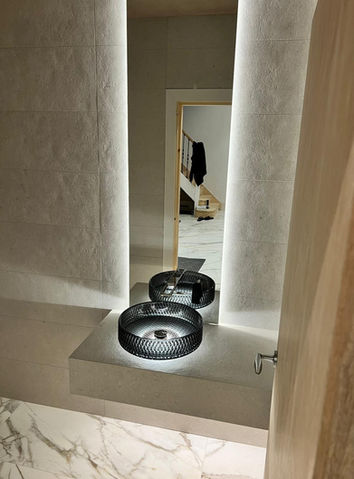 Modern black circular sink with underlighting and backlit mirror reflection.