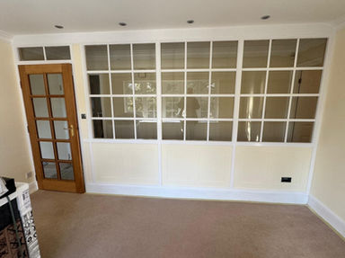 Interior room with large white grid window and wooden paneled glass door.
