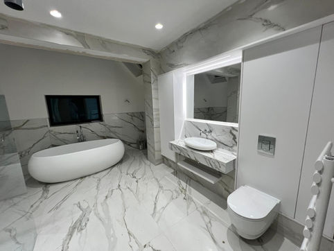 Elegant modern bathroom interior with white oval tub, marble, toilet, and TV.