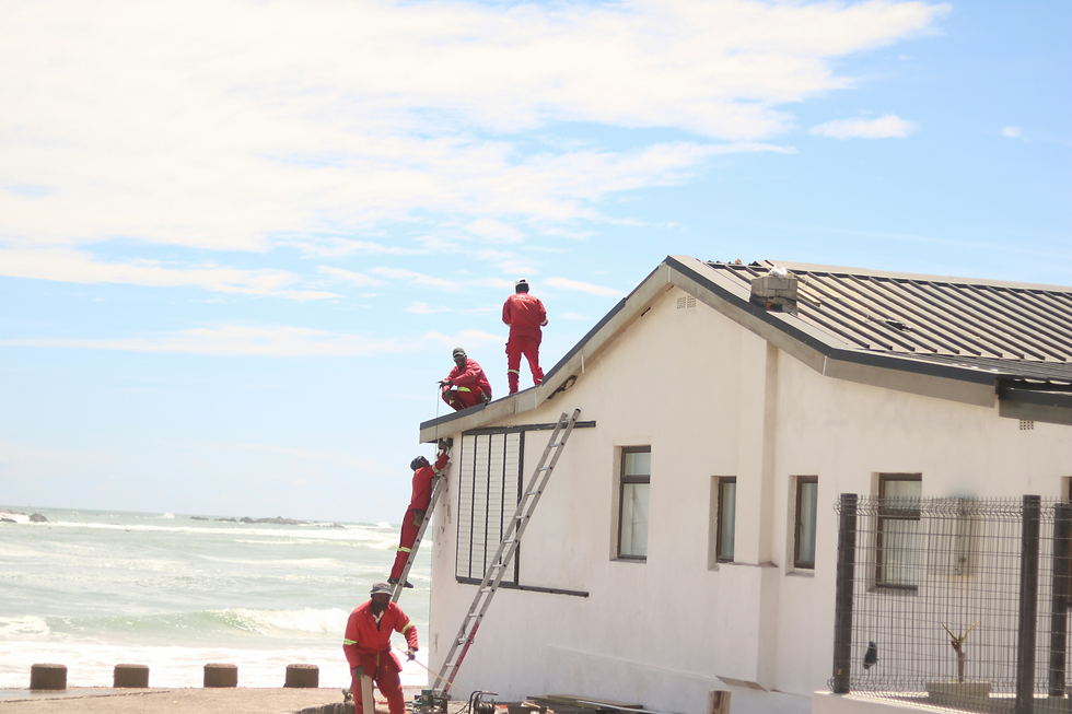 Workers in red suits on a white building roof_edited.png