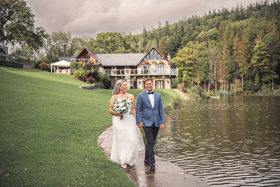 Sophie and Michael walk next to the lake at their wedding at Canada Lodge and Lake, Cardiff, photographed by Swansea Wedding Photographer, Katy Tainton Photography