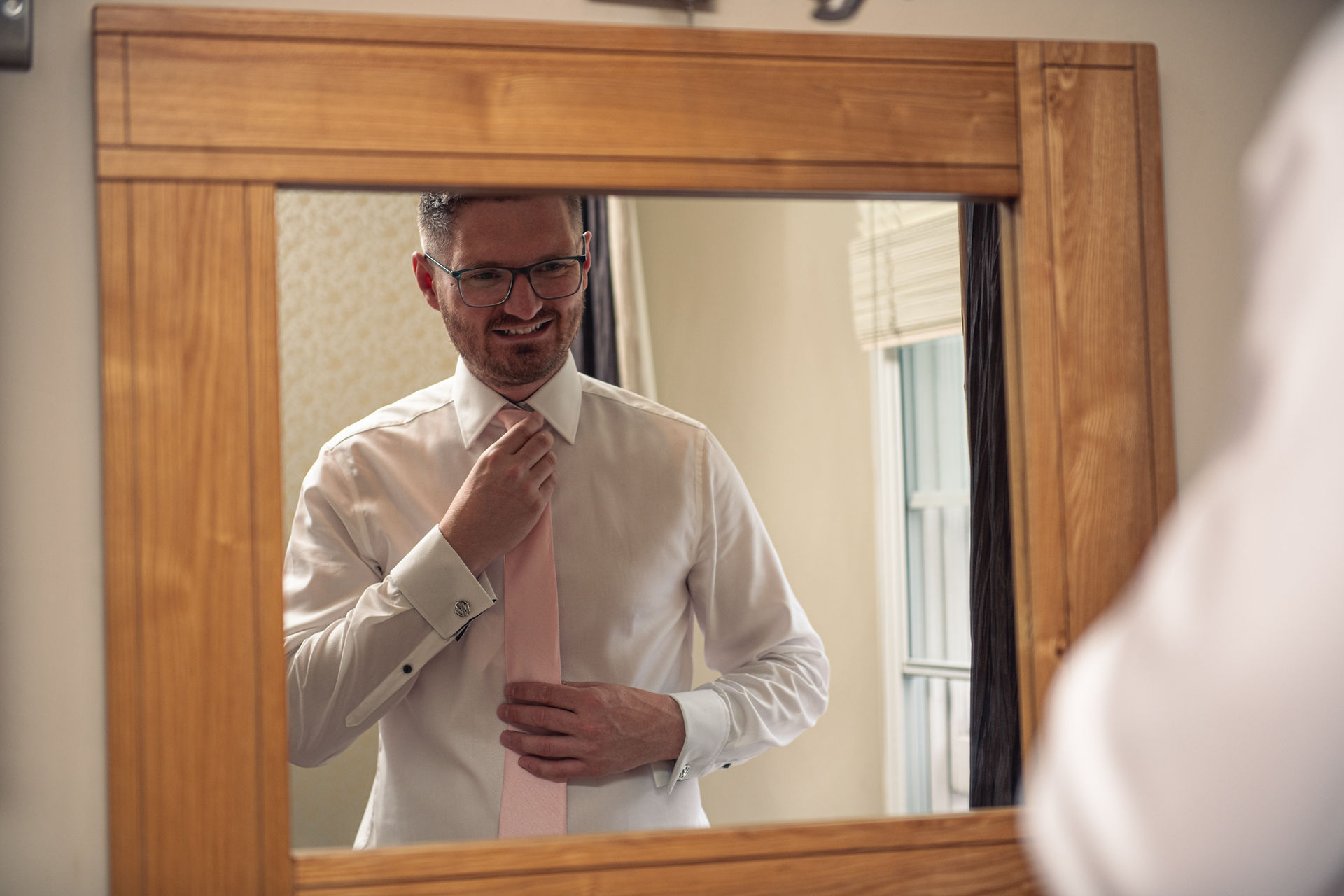 The groom does up his tie at a wedding at the Emlyn Hotel in Carmarthenshire, photographed by Swansea wedding photographer Katy Tainton Photography