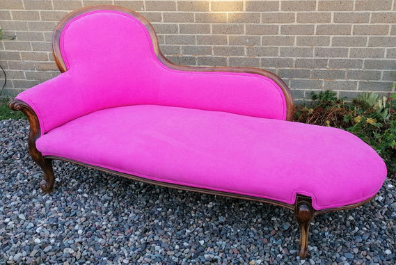 An electric-pink upholstered chaise-longue, photographed outside prior to loading in the van for delivery to the client. Unseen are the many hours undoing two botch jobs of reupholstery which included leaving old fabric in place such that it caused strange bulges, spoiling the curves of the piece.