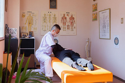 整体院の施術室でベッドにうつ伏せになった方へ整体施術を行っている様子