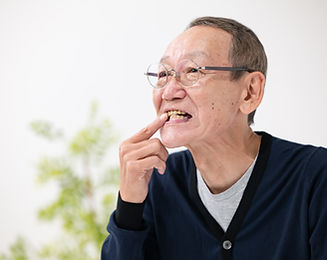 歯を指さす高齢男性