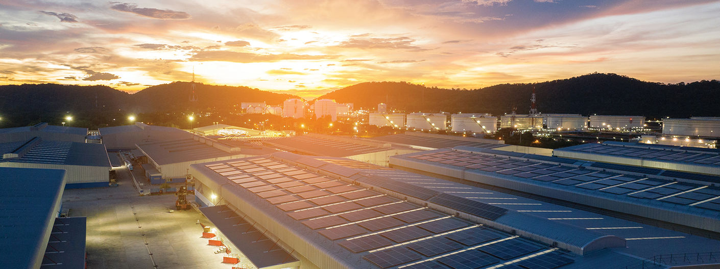 Rooftop solar panel installation across an industrial facility at sunset.