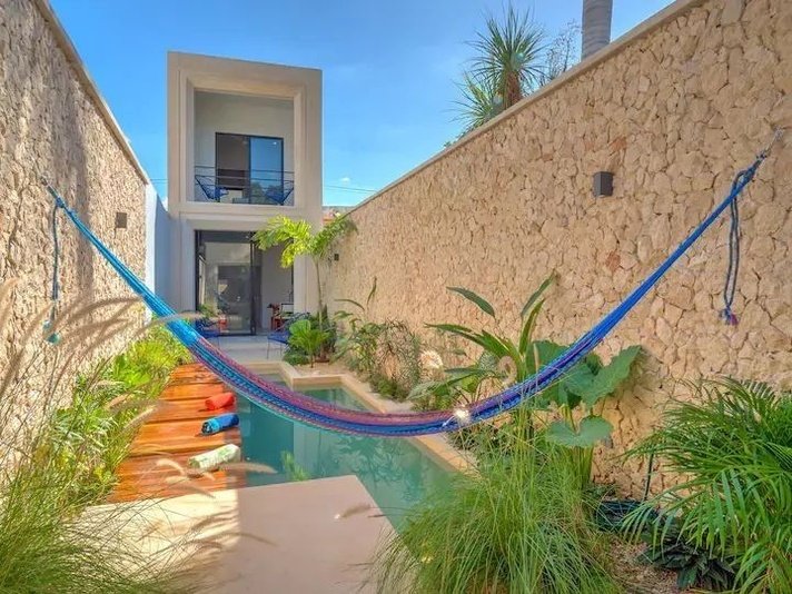 a hammock hanging from the side of a house next to a swimming pool