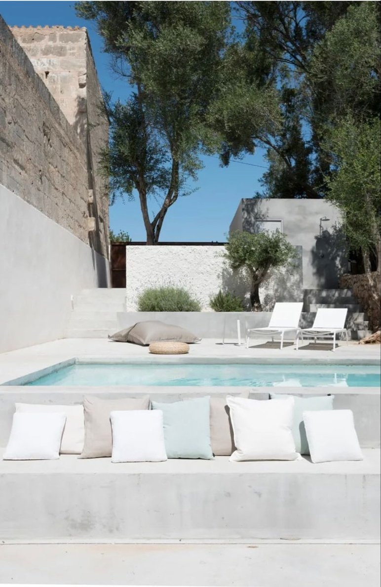 an outdoor pool with lounge chairs and trees in the backgrounge