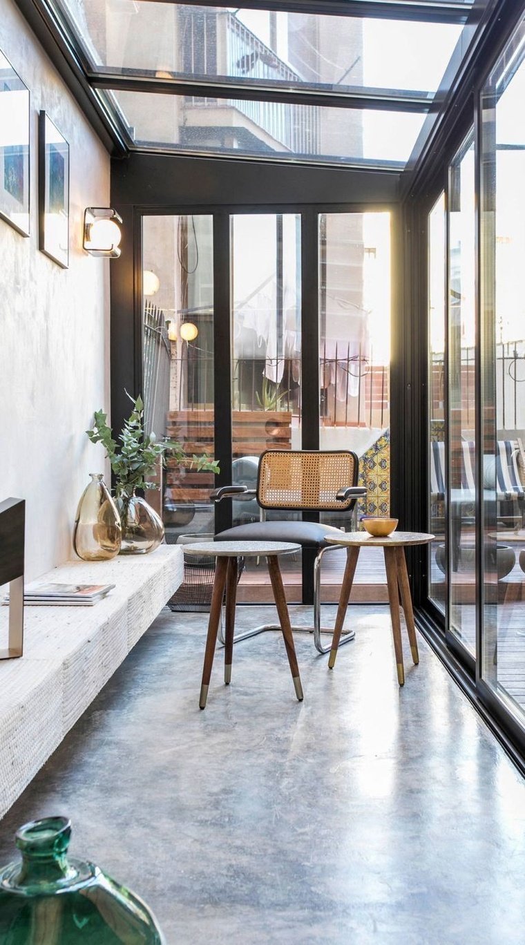 a living room filled with lots of furniture next to a glass wall covered in windows