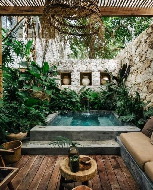 an outdoor living area with a pool surrounded by greenery and potted plants on the floor