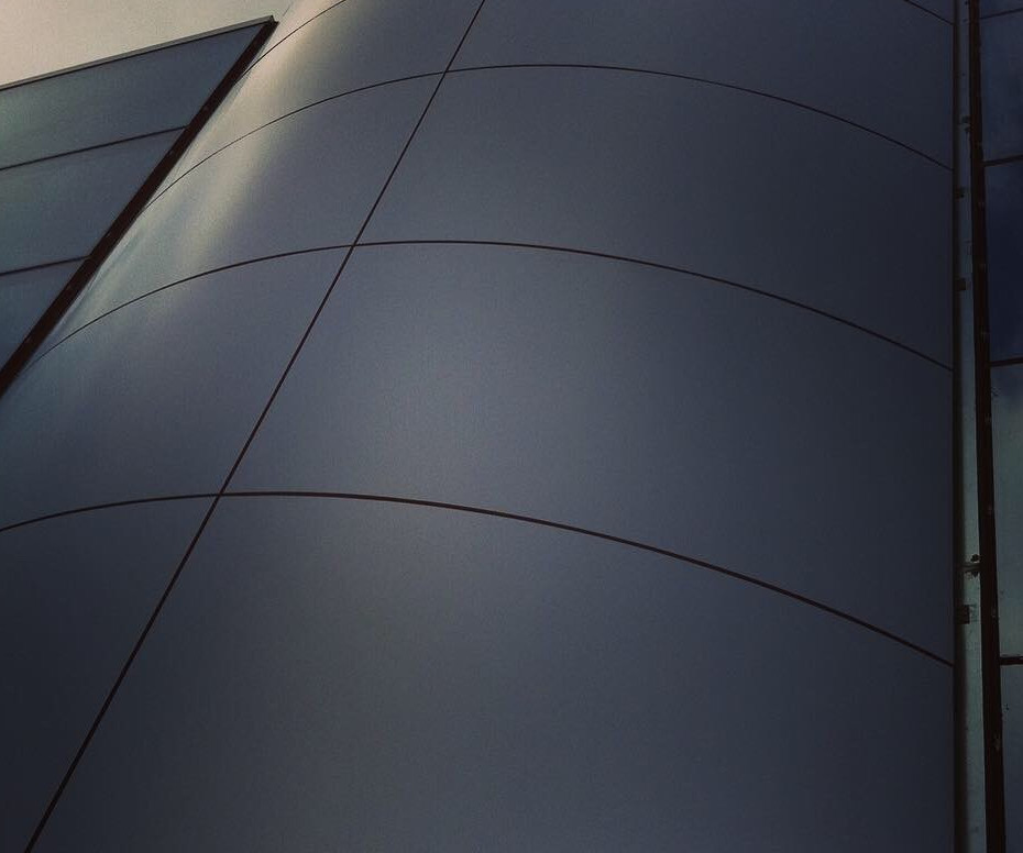 Facciaa ventilata in alucobond dal colore grigio opaco. E' una struttura verticale tonda composta da lastre in alucobond a forma rettangolare