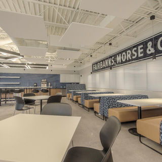 Open employee break room with communal seating, decorative lighting, shuffleboard table, and custom Fairbanks branding integrated throughout the space.