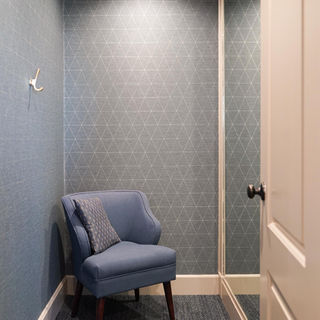 Private seating alcove in the renovated Blue Hills Country Club pro shop featuring a comfortable upholstered chair, textured blue wallcovering, and contemporary interior finishes.