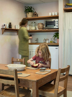 a little girl sitting at a table cutting an apple