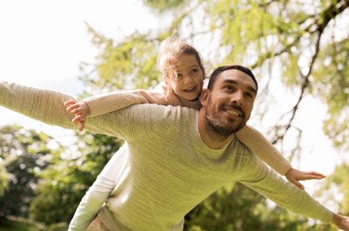 A mother and father with their biological and adopted daughter, a father with his little girl on his back, playing aeroplane