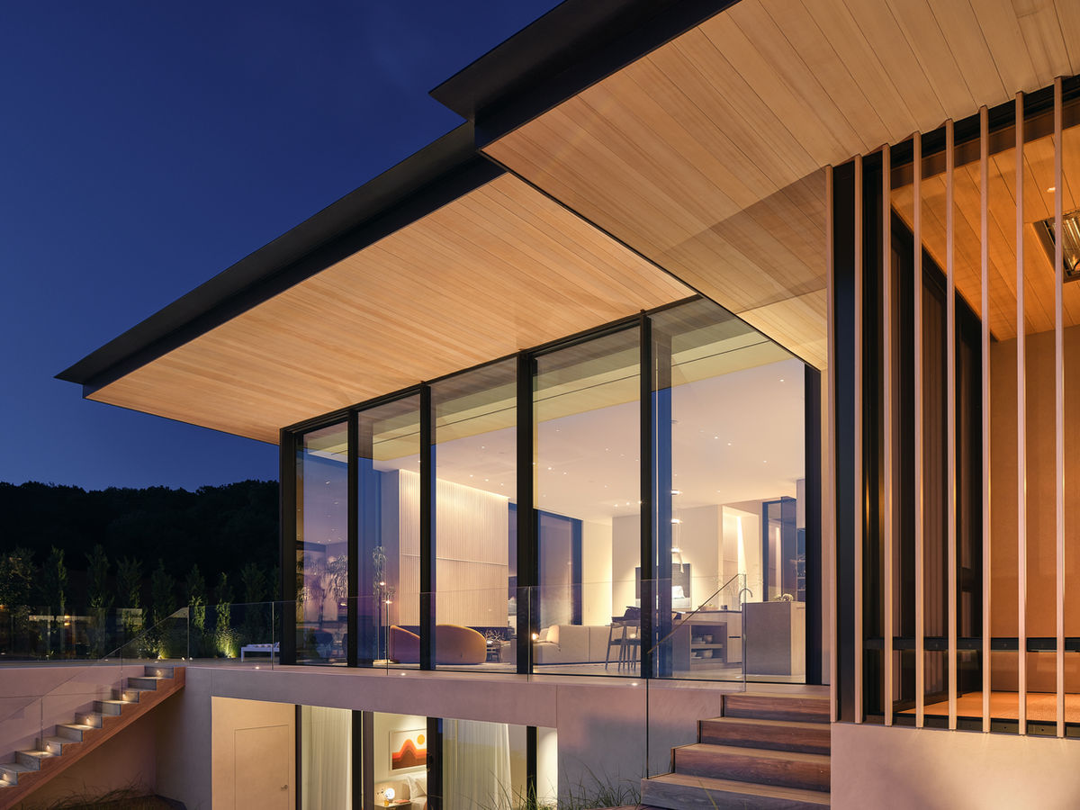 Biophilic, modern home at night. Built to emerge from the dunes this home is lit up by lights that highlight the design at night.